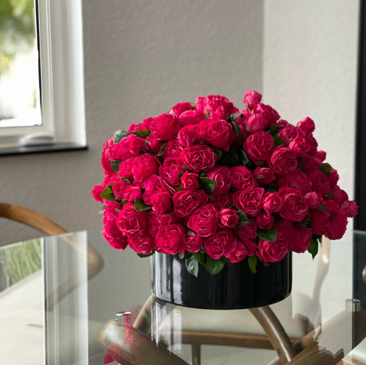 Dark pink English roses in a black glass vase.
